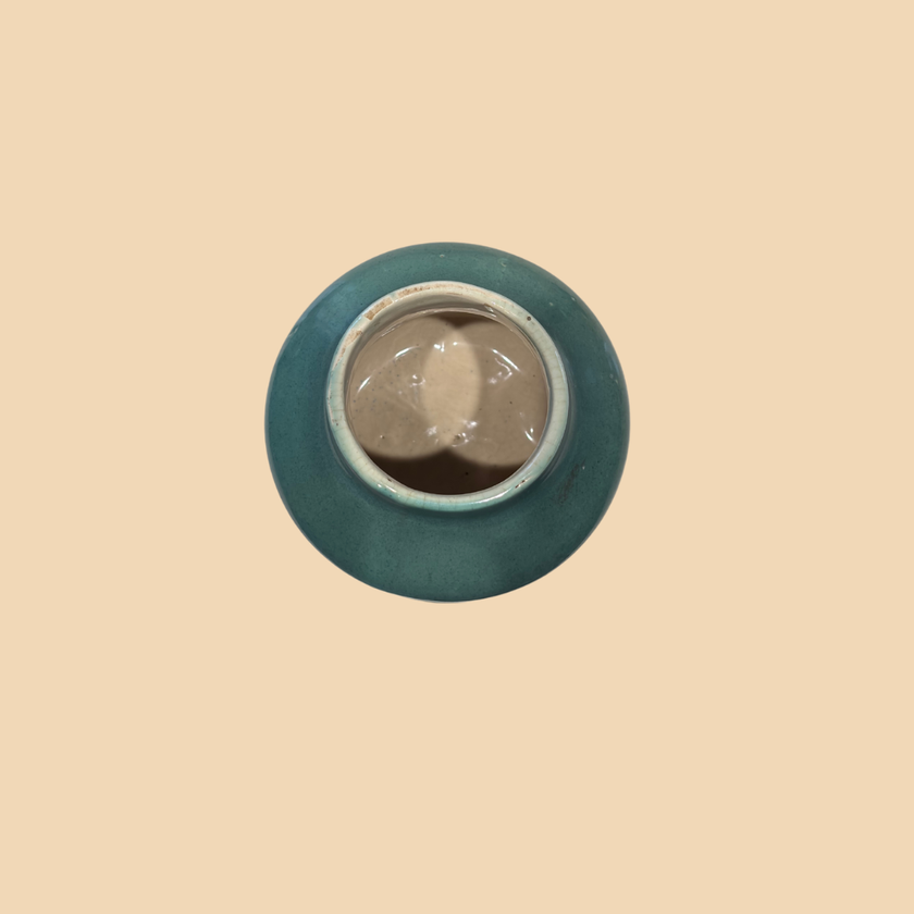 Round metallic object with blue rim on a beige background